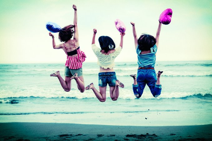 海辺でジャンプする三人の女性