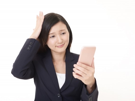 スマホを見て頭を抱える女性